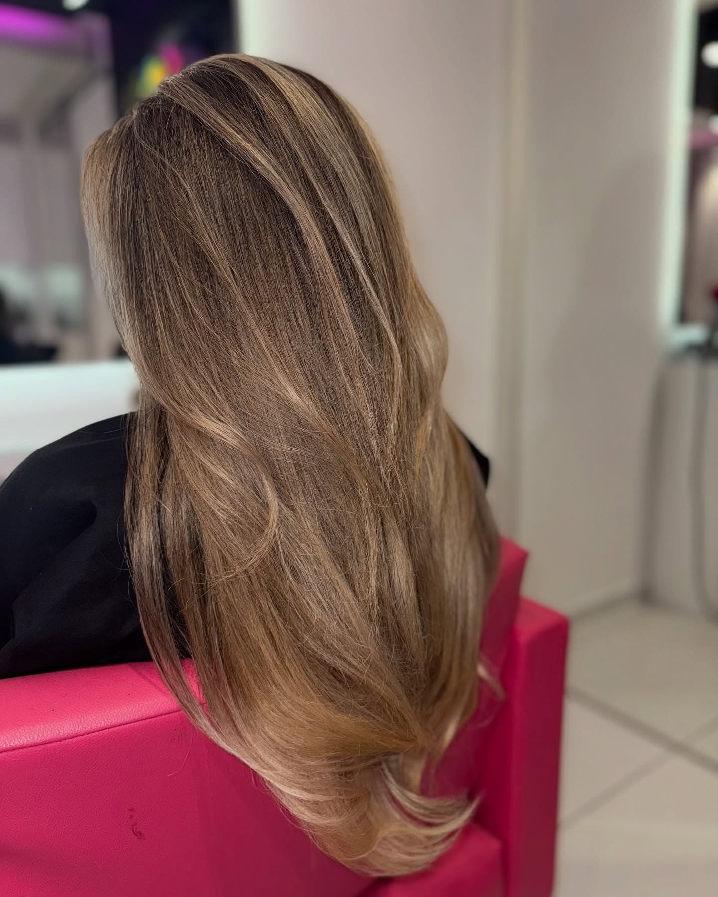 Lange Längen in Bronde auf einem pinken Sessel